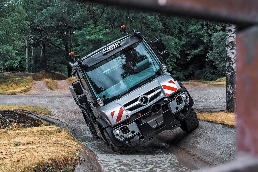 Unimog, dirigindo por uma poça profunda de água em duas rodas - front
